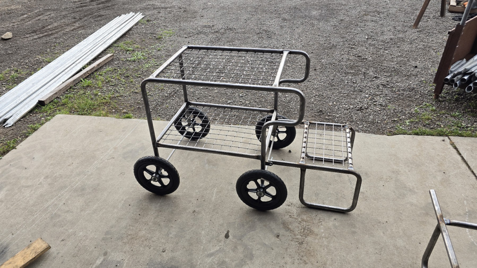 A Tunnel Tech picking cart: a tubular steel frame on four wheels with two wire mesh shelves, a push handle and a side tray.